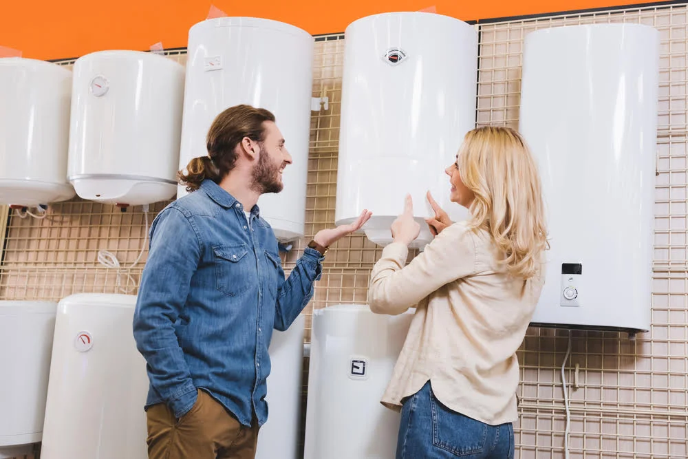 A man and a woman standing next to a wall of water heaters.